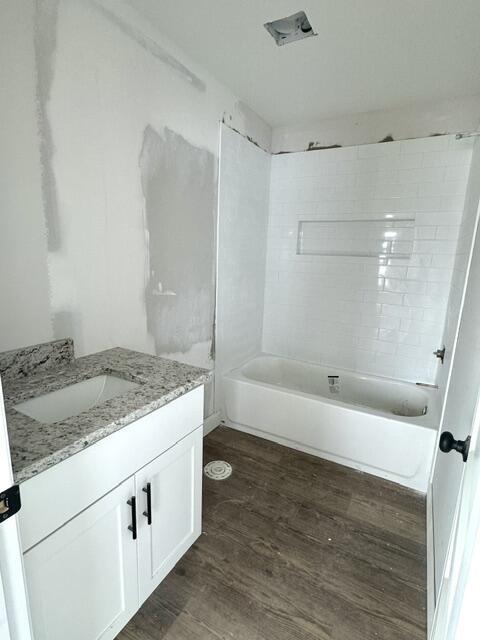 bathroom with vanity, wood-type flooring, and tiled shower / bath