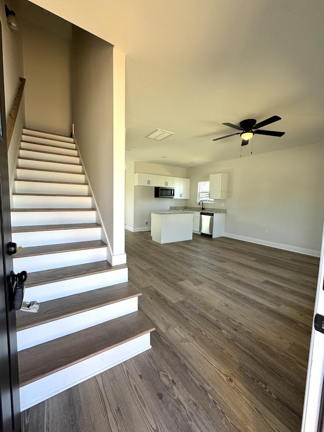 stairway featuring ceiling fan, wood finished floors, visible vents, and baseboards