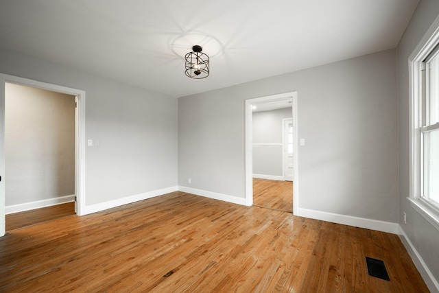 spare room with light hardwood / wood-style floors and an inviting chandelier