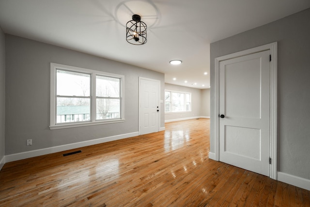 empty room with hardwood / wood-style floors, an inviting chandelier, and plenty of natural light