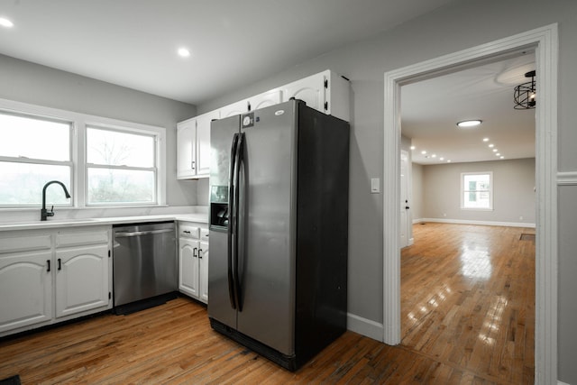 kitchen with white cabinets, stainless steel appliances, light hardwood / wood-style flooring, and sink