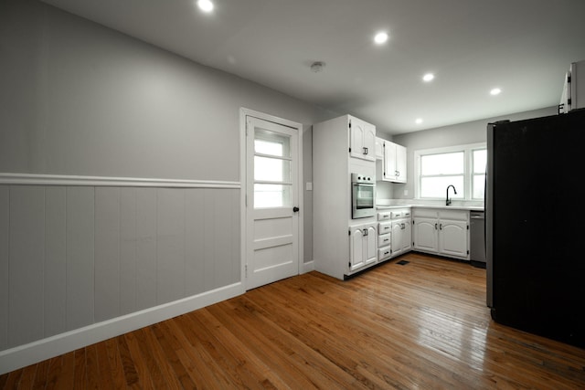 kitchen featuring white cabinets, stainless steel appliances, light hardwood / wood-style flooring, and a wealth of natural light