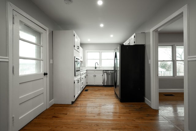 kitchen featuring appliances with stainless steel finishes, light hardwood / wood-style floors, white cabinetry, and plenty of natural light