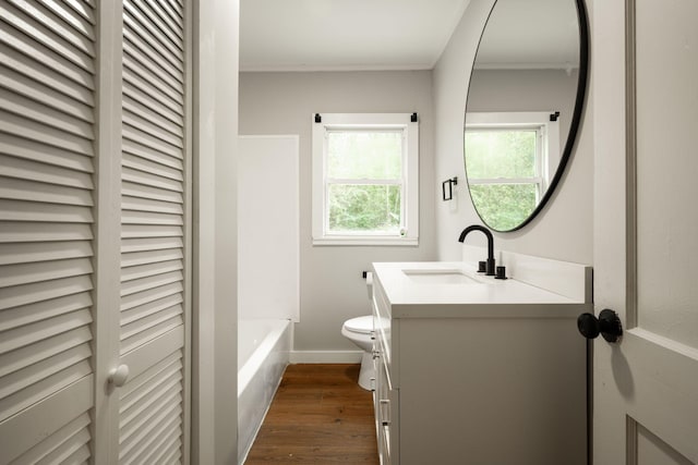 bathroom with hardwood / wood-style floors, vanity, a tub to relax in, and toilet