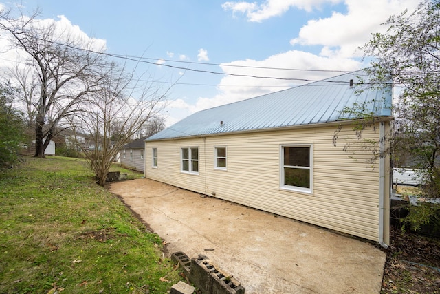 back of house with a lawn and a patio