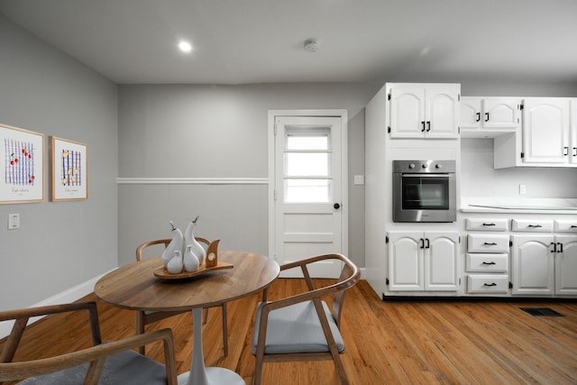 kitchen with white cabinets, light wood-type flooring, and stainless steel oven