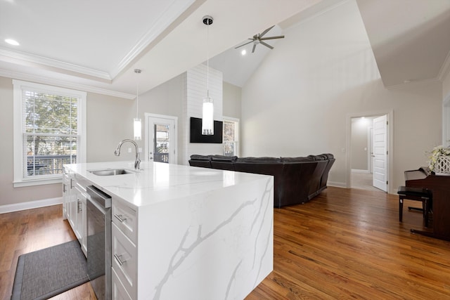 kitchen featuring white cabinetry, an island with sink, light stone counters, and decorative light fixtures