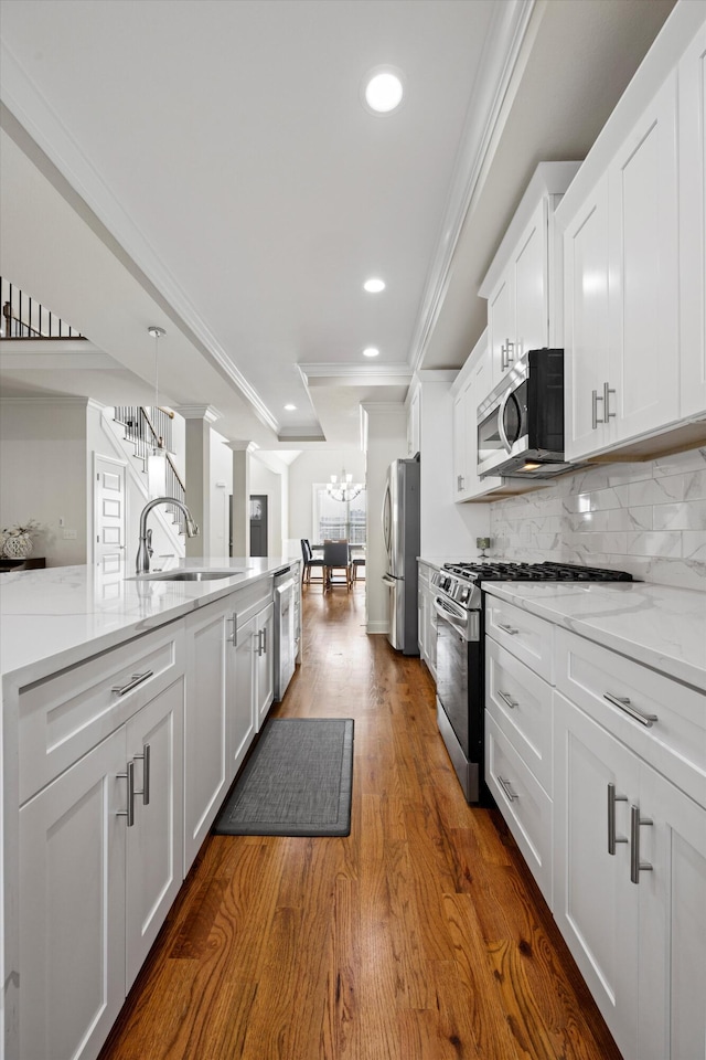 kitchen with white cabinetry, sink, decorative backsplash, appliances with stainless steel finishes, and ornamental molding