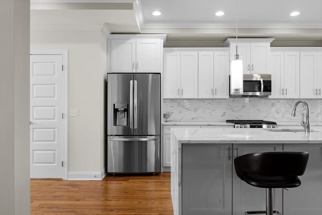 kitchen featuring light stone countertops, sink, appliances with stainless steel finishes, white cabinets, and ornamental molding