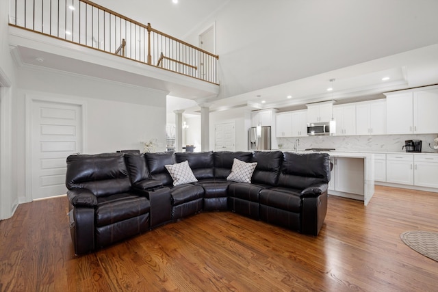 living room with hardwood / wood-style floors, a towering ceiling, and decorative columns