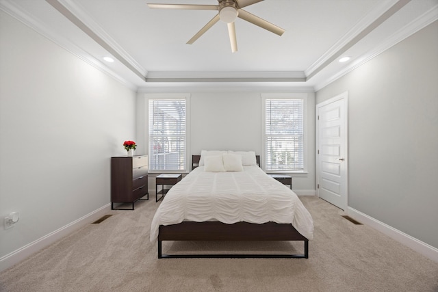 carpeted bedroom with ceiling fan, ornamental molding, and a tray ceiling