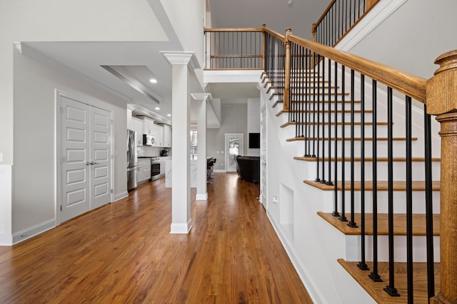 foyer entrance with hardwood / wood-style floors, decorative columns, and ornamental molding