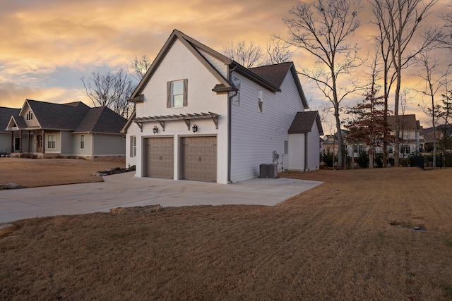 property exterior at dusk featuring a yard, a garage, and central air condition unit