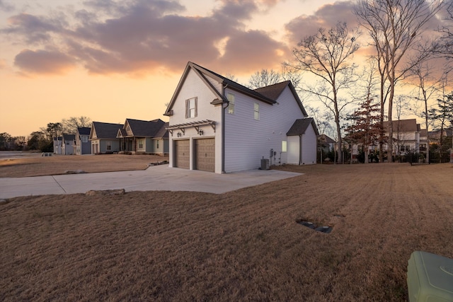 property exterior at dusk featuring central air condition unit and a garage