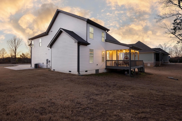 back house at dusk with covered porch and central air condition unit