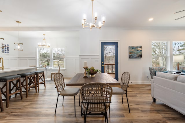 dining space with hardwood / wood-style flooring, plenty of natural light, and a notable chandelier