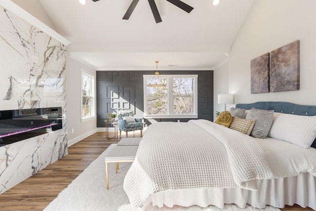 bedroom with multiple windows, ceiling fan, wood-type flooring, and lofted ceiling