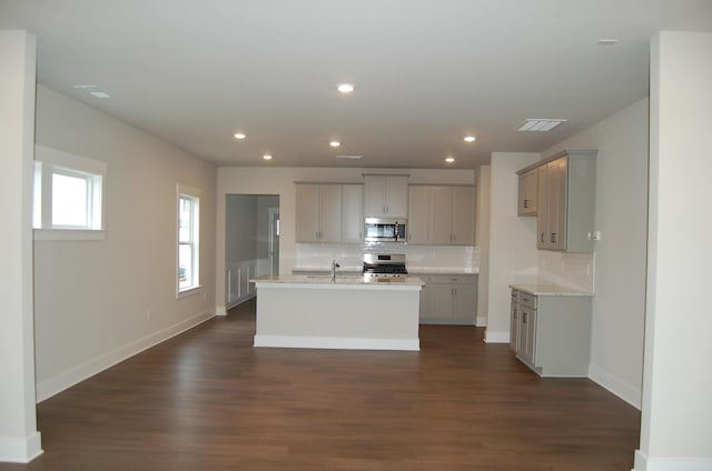 kitchen featuring appliances with stainless steel finishes, backsplash, dark hardwood / wood-style flooring, a kitchen island with sink, and gray cabinets