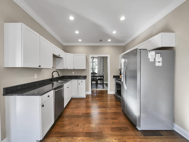 kitchen featuring dark wood-type flooring, sink, dark stone countertops, appliances with stainless steel finishes, and white cabinetry