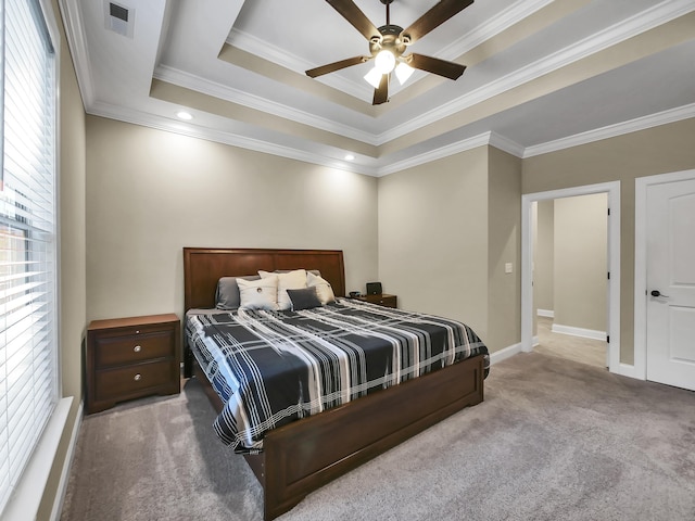 carpeted bedroom with a raised ceiling, multiple windows, ceiling fan, and crown molding