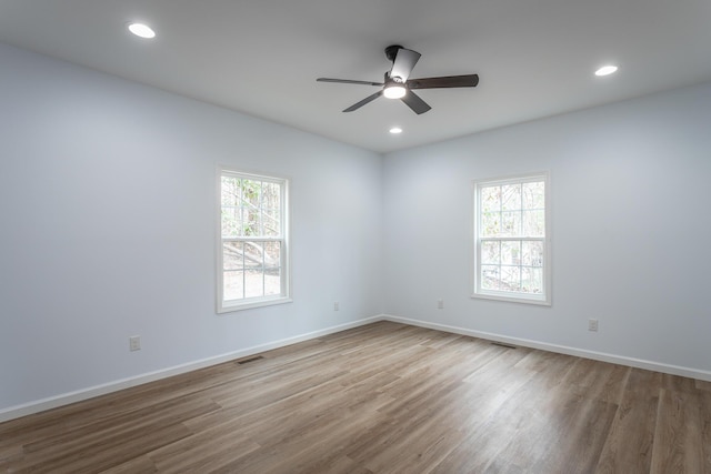 spare room featuring ceiling fan, a wealth of natural light, and light wood-type flooring