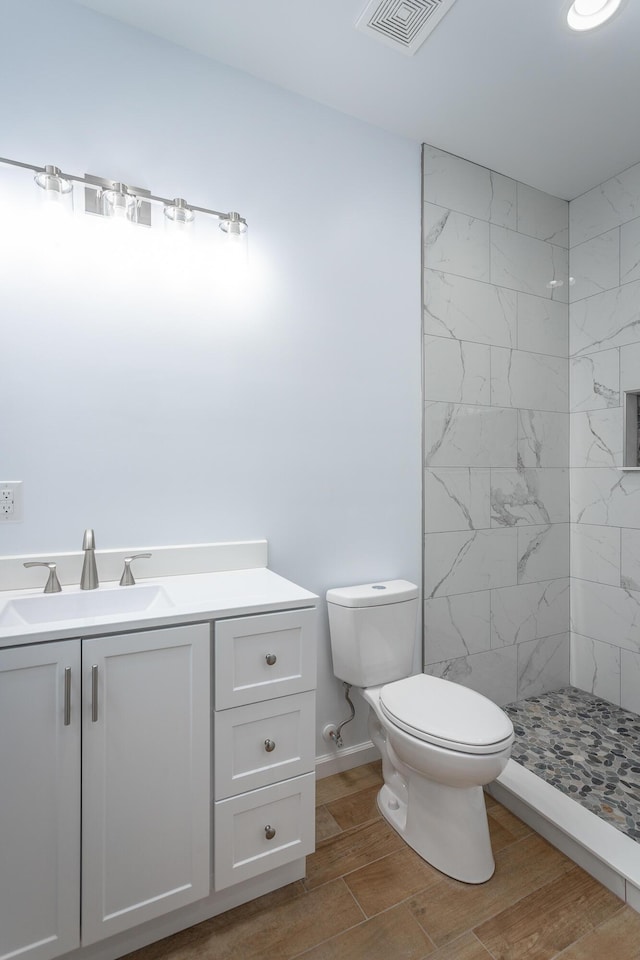 bathroom featuring vanity, toilet, and a tile shower