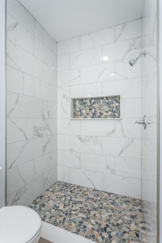 bathroom with a tile shower and toilet