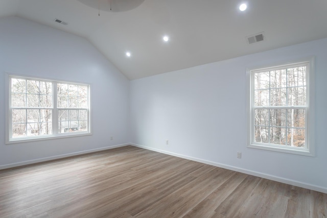 spare room featuring light wood-type flooring and vaulted ceiling