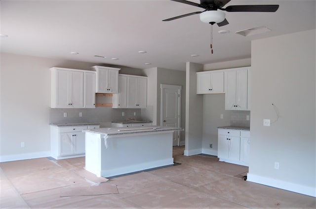 kitchen with white cabinetry, a kitchen island, tasteful backsplash, and ceiling fan