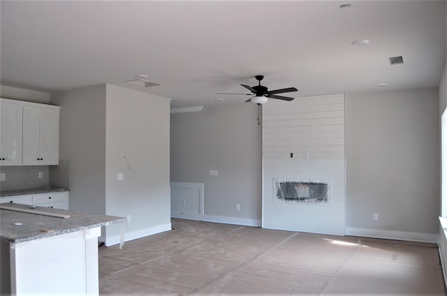 kitchen featuring ceiling fan, light stone counters, white cabinetry, and tasteful backsplash