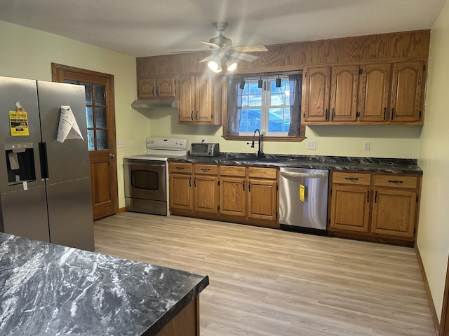 kitchen featuring under cabinet range hood, appliances with stainless steel finishes, a sink, and brown cabinets