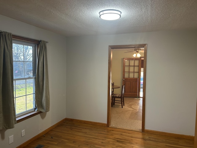 unfurnished room featuring plenty of natural light, wood finished floors, and baseboards