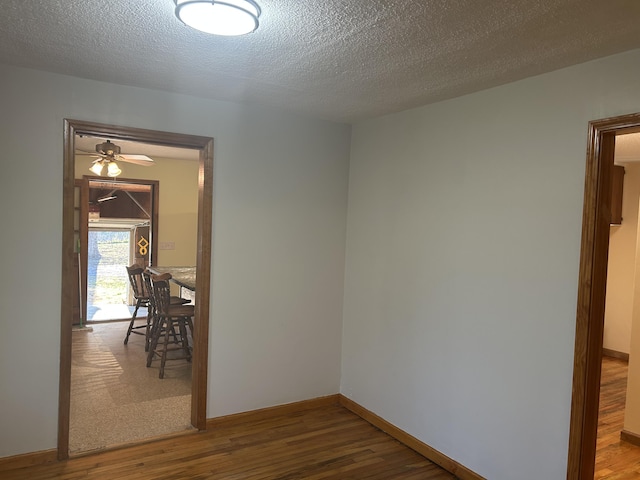 empty room featuring a textured ceiling, baseboards, and wood finished floors