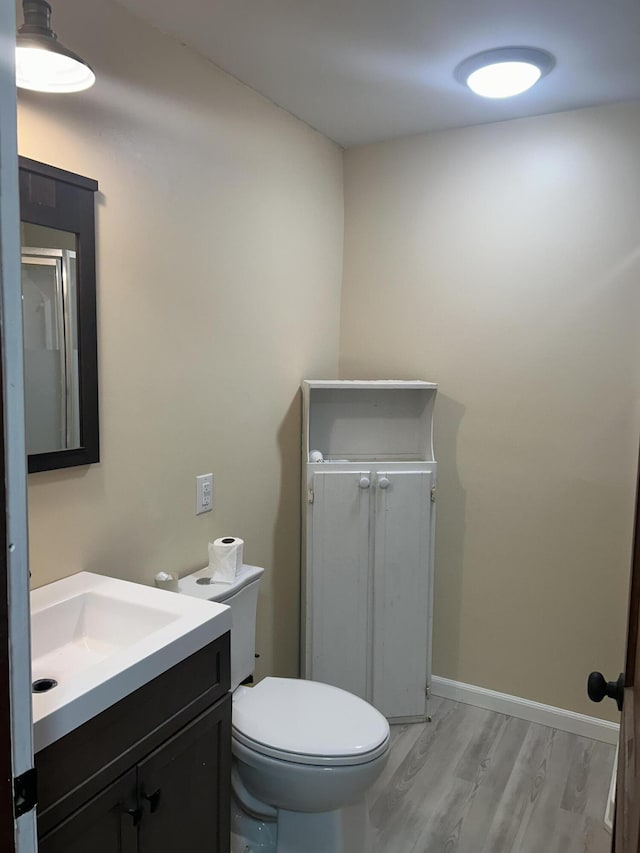 bathroom with toilet, baseboards, wood finished floors, and vanity