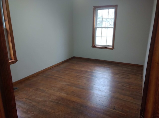 empty room featuring baseboards and dark wood finished floors