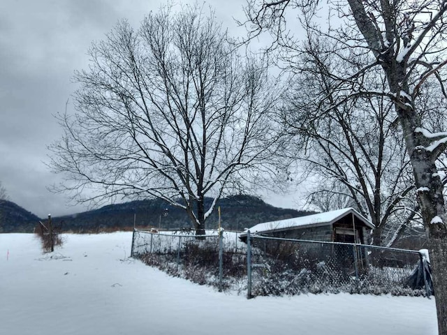 yard layered in snow featuring fence and a mountain view