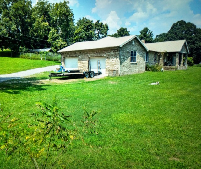 exterior space with a garage, stone siding, a chimney, and a yard