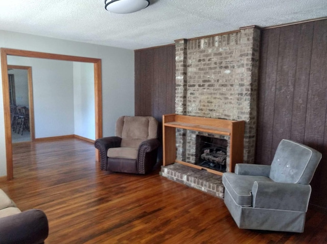 living room with wood walls, a fireplace, and dark wood-style flooring