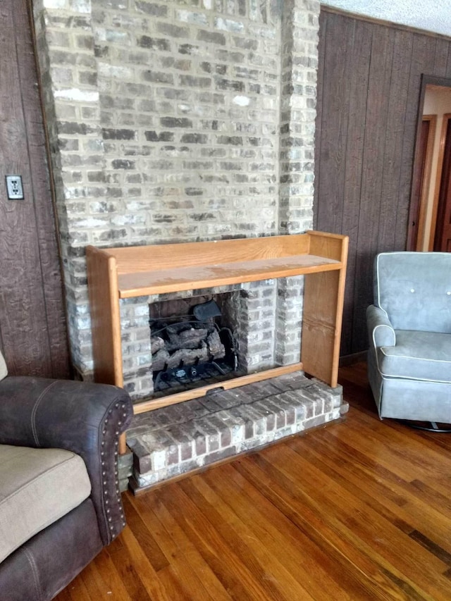 sitting room with wood walls, a fireplace, and wood finished floors