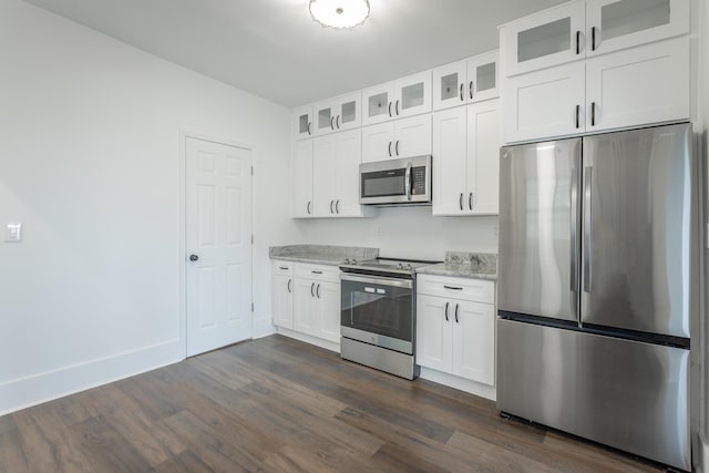 kitchen with white cabinets, dark hardwood / wood-style flooring, light stone countertops, and stainless steel appliances