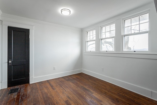 empty room featuring dark hardwood / wood-style flooring and crown molding