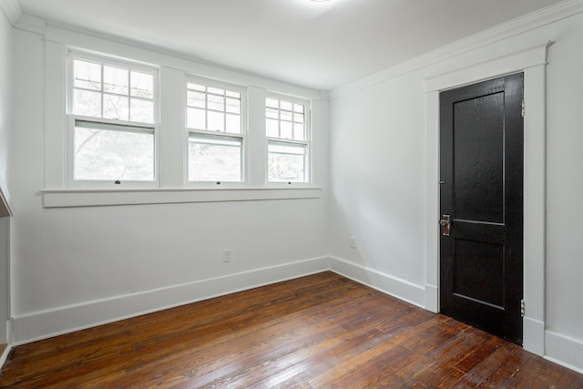 empty room with crown molding and dark wood-type flooring