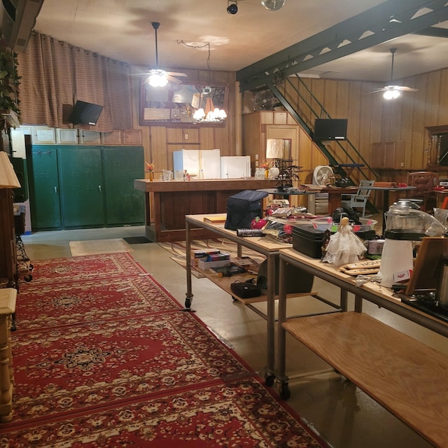 interior space featuring ceiling fan with notable chandelier and wood walls