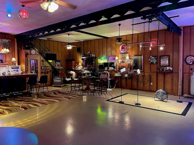 bar with ceiling fan, concrete floors, pendant lighting, and wooden walls