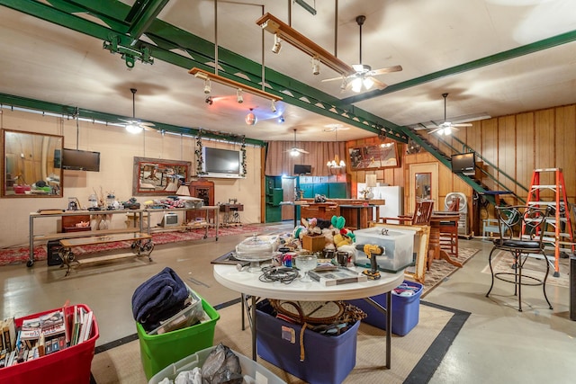 dining area featuring ceiling fan, wood walls, and a workshop area