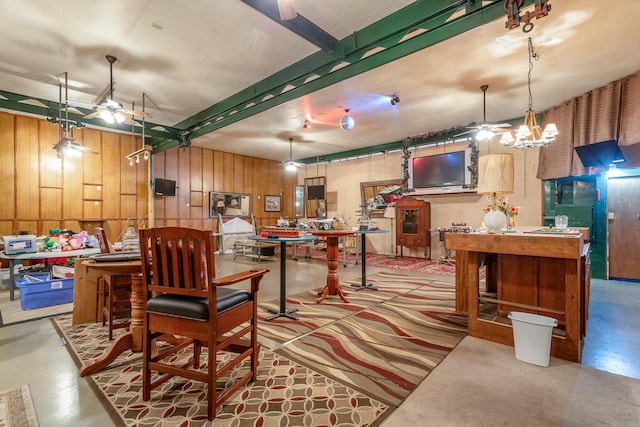 dining space with ceiling fan, concrete floors, and wood walls