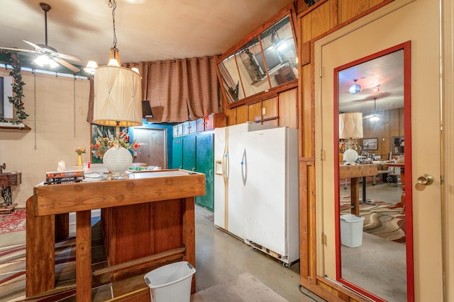 kitchen featuring ceiling fan, concrete floors, and white fridge with ice dispenser