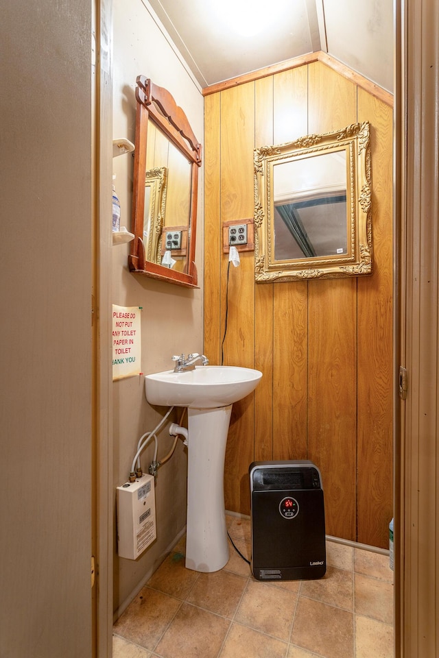 bathroom featuring wood walls, sink, and lofted ceiling