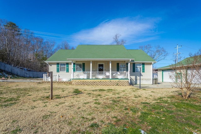 view of front facade with a front yard, covered porch, a garage, and an outbuilding