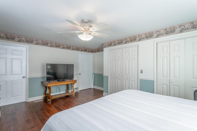 bedroom featuring dark wood-type flooring, ceiling fan, and two closets